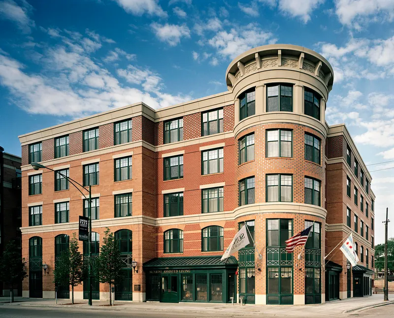 Red-brick multi-family building with a rounded corner and ground-floor retail
